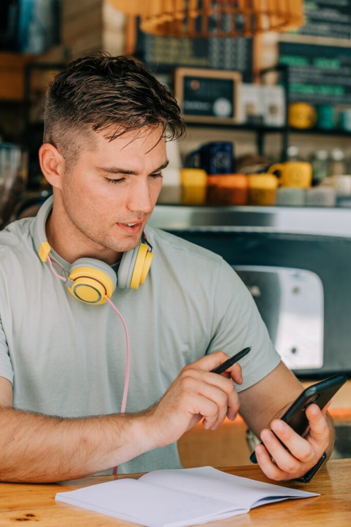 Stylish male studen sits at table in a cafe with mobile phone